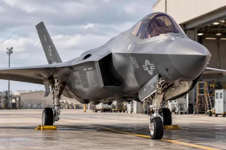Military fighter jet parked on an airfield outside an aircraft maintenance hangar